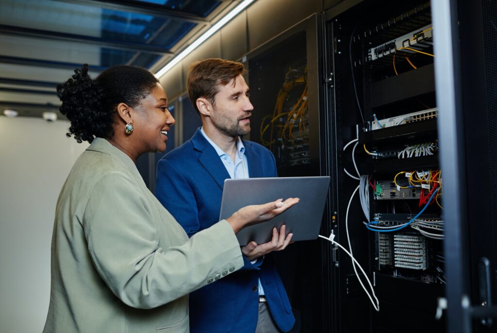 To personer som ser på en server. Daglig leder har ikke til venstre har spørsmål til hvordan systemet fungerer og hvordan vi bedre kan sikre sikkerheten fra dataangrep.